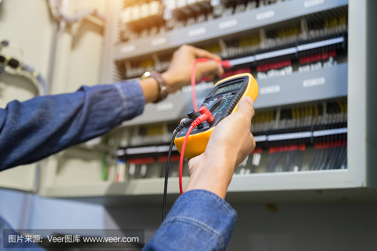 电工工程师在电控箱控制中进行电力线路电压和电流的测试。